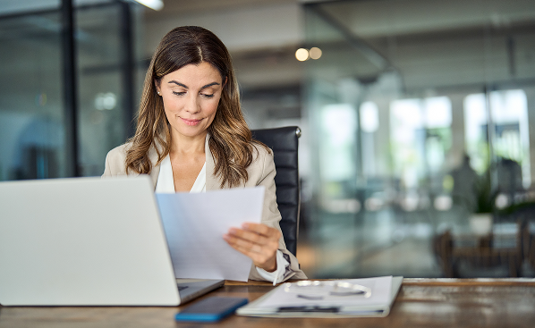 Business executive handling payroll at desk with paper in hand